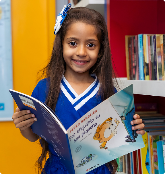 Menina sorridente segurando um livro em uma biblioteca colorida do Colégio Centro de Estudos
