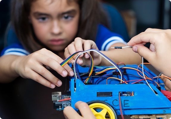 Criança montando um robô com circuitos eletrônicos em atividade de tecnologia